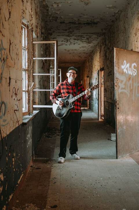 Crazy Chris Loony im Flur mit Gitarre